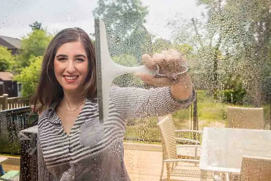 Melissa cleaning a window with a squeegee